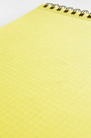 Wire spiral unlined clean yellow checkered lined paper isolated on white backgroundの写真素材