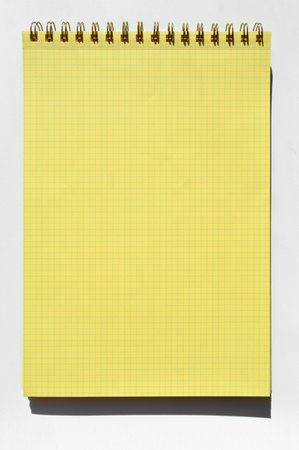 Wire spiral unlined clean yellow checkered lined paper isolated on white background