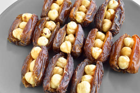 Organic fresh nutritious dried dates dates medjool grains, hazelnuts placed inside the date, in a gray plateの写真素材