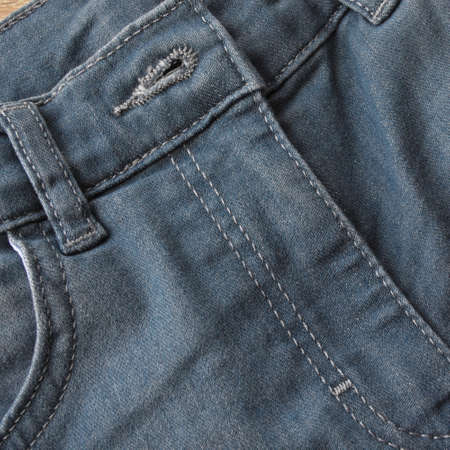 Close up detail of pocket and button front view of light blue jeans denimの写真素材