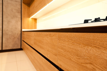 Modern brown wood oak kitchen cabinet equipment, stylish white granite countertops and glass gas stove in a homeの写真素材