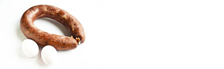 Homemade coiled sausage made of various spice mixes used in Turkish cuisine and two white eggs, isolated on white backgroundの写真素材