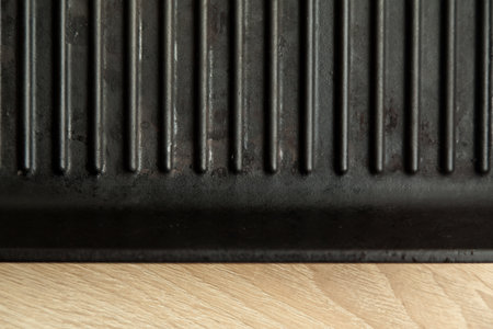 Empty black cast heavy iron grill pan on modern oak kitchen countertop, modern kitchen equipmentの写真素材