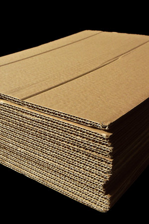 Brown and beige colored corrugated cardboard detail, isolated on black backgroundの写真素材
