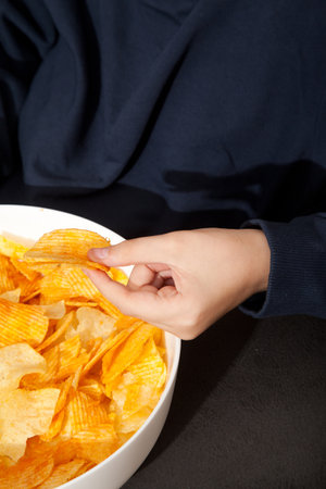 Caucasian person in navy blue t-shirt holding white plate full of potato chips and preparing to eatの写真素材