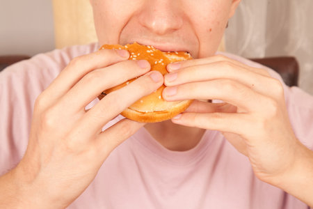 A Caucasian man eats half-eaten sesame fresh hamburger, American fast food cultureの写真素材