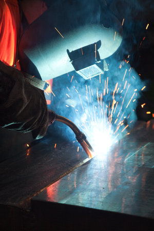 Welder uses torch to make sparks during manufacture of metal equipment, industrial professional welding masterの写真素材