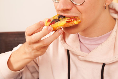 Bearded Caucasian male in pink t-shirt eating delicious and wonderful pizza slices