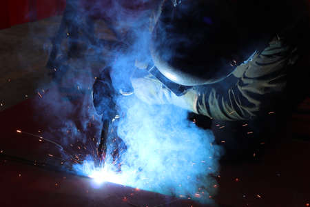 Welder at work in the factory. The welder is welding metal.