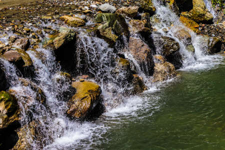 Mountain stream with clear water and stones on a sunny day.