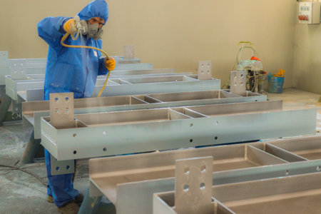 The painter is working to painting the steel structure with spray gun at industrial factory