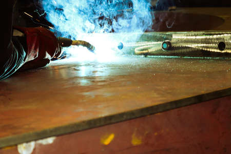 welder at work, closeup of hands working with arc welding machine