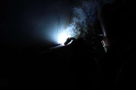 Silhouette of a welder working in a construction site.