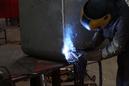 welder at work in a factory welding metal with sparks. High quality photo