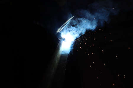 Welding of steel structures with sparks and smoke from welding.