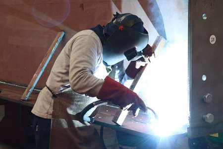 Welder at work in a factory, welding with arc welding machine