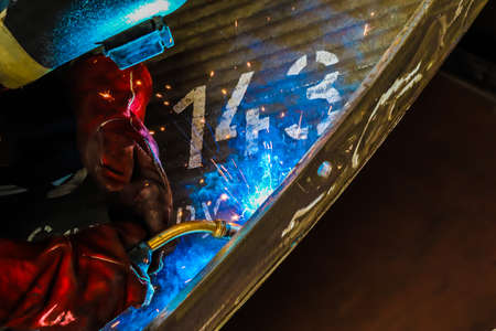 Welder welds metal structures using electric arc welding machine to weld steel.