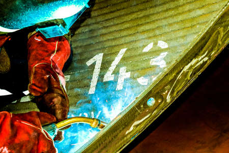 A closeup shot of a person welding a metal surface with a blurred background