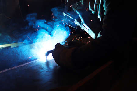 Welder working with arc welding machine in factory. Metalwork manufacturing and construction...