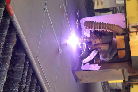 Industrial welder cutting metal with arc welding machine in factory.