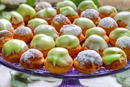 Delicious sweet buffet with vivid green profiteroles on glass trayの写真素材
