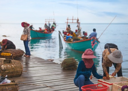 Traditional asian fishing. Cambodian men on the fishing boat pass the catch of  blue crabs to woman for saleのeditorial素材