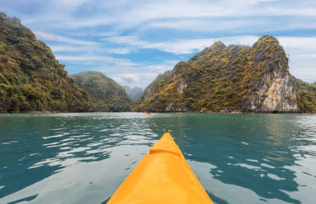 Yellow kayak on turquoise sea water amongst the rocks of Halong Bayの写真素材