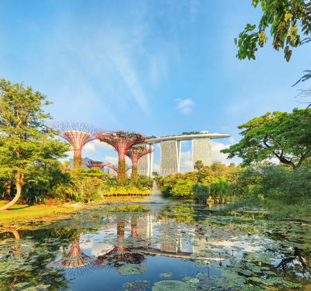 Singapore, Republic of Singapore - May 5, 2016: Gardens by the Bay with Supertree grove and Marina bay Sands hotel reflecting in lake at sunriseのeditorial素材
