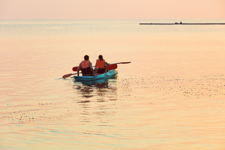 Lonely couple in kayak in the middle of the ocean at sunsetの写真素材