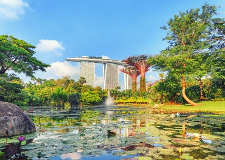 Singapore, Republic of Singapore - May 5, 2016: Gardens by the Bay with Supertree grove and Marina bay Sands hotel reflecting in lake at sunriseのeditorial素材