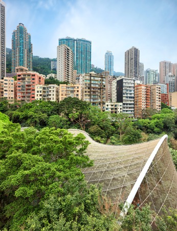 View on residential area of Hong Kong with high-rise apartment buildings rising over Hong Kong Park with Edward Youde Aviary dome of birds exibitionの写真素材