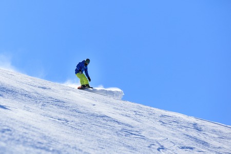 Male snowboarder on the slope sliding down the hillの写真素材