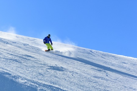 Male snowboarder on the slope sliding down the slopeの写真素材