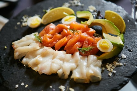 Seafood and salad on black plate close up