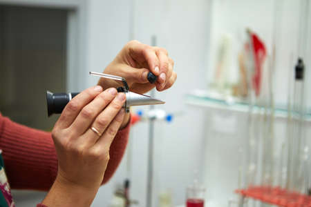 A woman squeezes grapes into a refractometer for measurementの写真素材