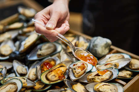 waiter adding sauce on mussels during cateringの写真素材