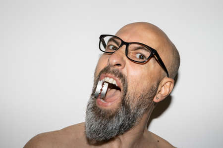 man with glasses and a blade in his mouth