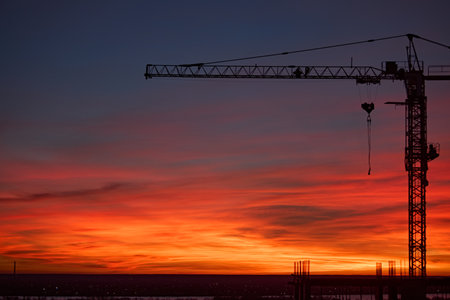 Silhouette of a construction crane against the background of the sunsetの写真素材