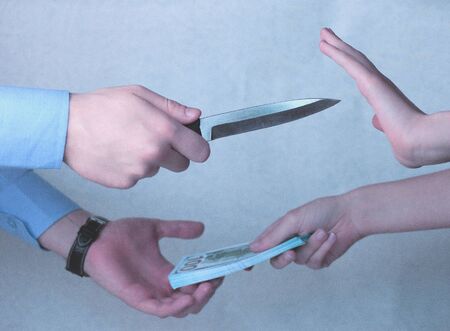 The man's hand threatens with a knife and takes the money, the woman 's hand is protected from the...