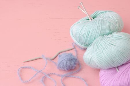 Skeins of blue lilac and turquoise yarn with knitting needles lie on the surface of the pink color.の写真素材