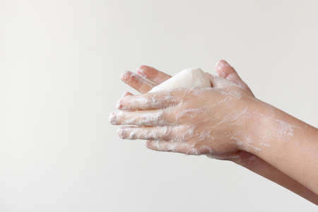 Two lathered hands hold soap between their palms on a white background. The concept of the need to wash hands to prevent diseasesの写真素材
