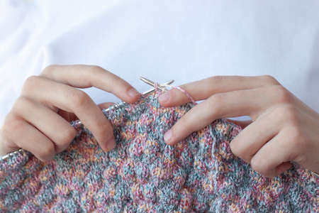 Two hands on a white background hold knitting needles and knitting close-up. The concept of hand made, home, Hobbies.の写真素材