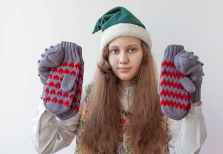 A girl in an elf hat holds several knitted mittens in her hands.の写真素材