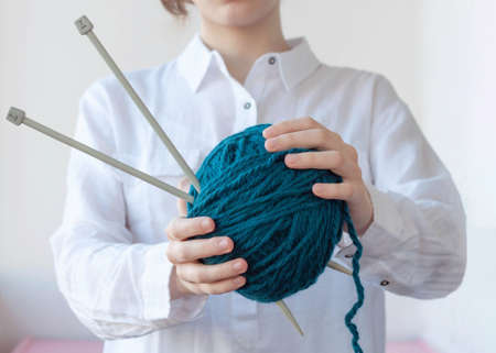 Two hands hold a large ball of yarn and knitting needlesの写真素材