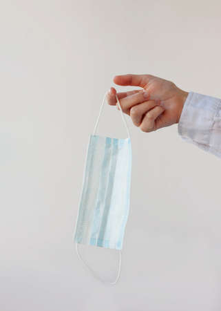 One hand holds a medical mask on the fingerの写真素材