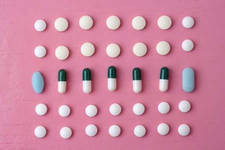 On a bright pink background, tablets of different sizes, colors and shapes are laid out in rows.の写真素材