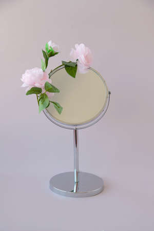 Round table mirror with three pink flowers on topの写真素材