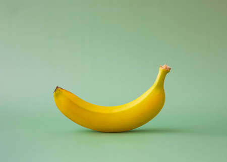 Yellow banana on green background background place for text side viewの写真素材