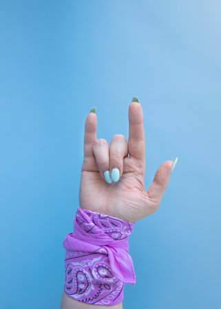 A hand with a pink bandana on the wrist shows two fingers an index finger and a little fingerの写真素材