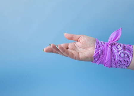 A hand with a pink bandana on the wrist turned open palm up